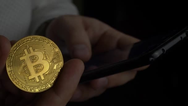 Comerciante sostiene Smartphone Negro y Bitcoin en la mano — Vídeo de stock