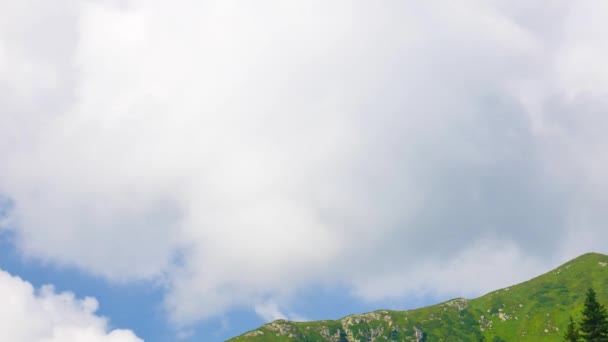 Nuvens brancas voam sobre a montanha com grama verde no fundo do céu azul — Vídeo de Stock