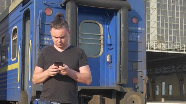 Traveler near trein wagon op trein station met smartphone — Stockvideo