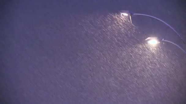 Nieve cayendo real en lámpara de calle en el fondo de la ciudad — Vídeos de Stock