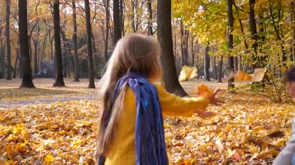 Père vomit feuilles jaunes sur petite fille heureuse au parc — Video