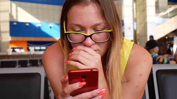 Жінка переглядає червоний смартфон в аеропорту — стокове відео