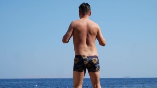 海の近くのビーチで踊り、日光浴をする男 — ストック動画