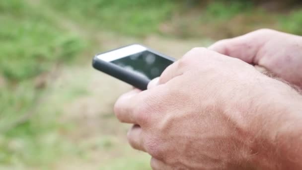 Mans Hands Using Smartphone on Green Grass Background — Stockvideo