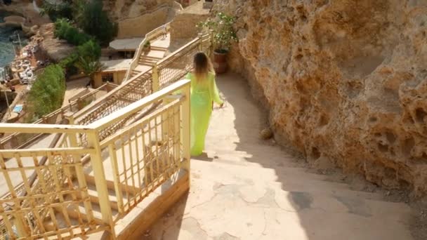 Mujer en pareo verde claro baja escaleras a la playa — Vídeo de stock