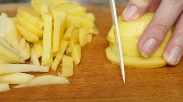 Κοπή πατάτες με μαχαίρι στο τραπέζι στη διαδικασία της μαγειρικής — Αρχείο Βίντεο