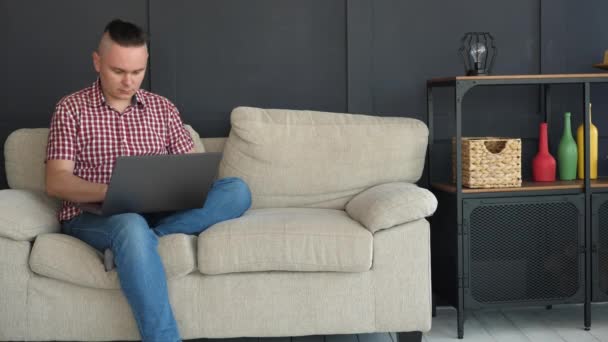 Hombre guapo está escribiendo texto en el ordenador portátil gris — Vídeos de Stock