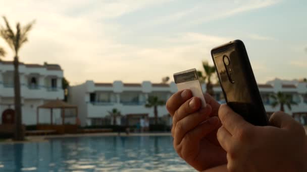Hand hålla Smartphone och betalkort på pool bakgrund — Stockvideo