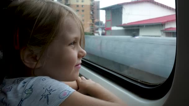 Menina pequena olha para fora janela do trem em carruagem durante a viagem — Vídeo de Stock