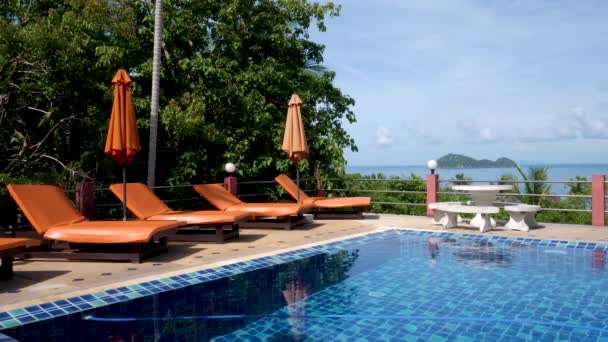 Piscine avec parasols orange et chaise de plage sur fond de mer — Video