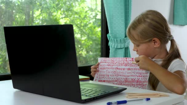 Child girl does school homework using laptop computer at home — Stock Video