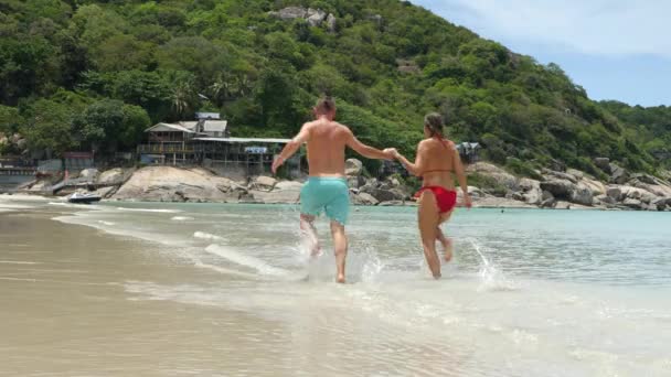 Gelukkig getrouwd stel rennen, springen en spelen op zee strand — Stockvideo