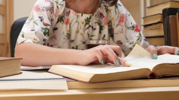 La mano femminile legge il libro e scrive le informazioni nel quaderno di carta — Video Stock