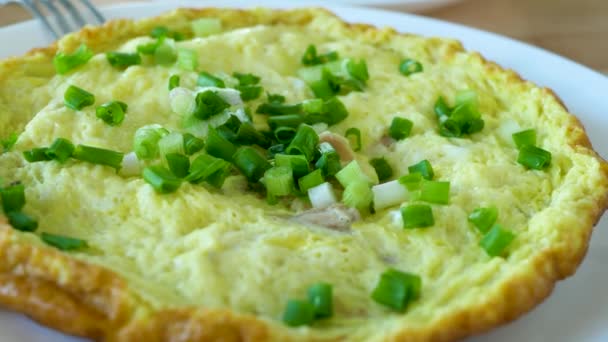 Omelet met groene ui geserveerd op witte plaat op tafel — Stockvideo