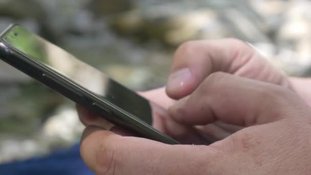 Usando Smartphone preto no fundo de fluxo de montanha — Vídeo de Stock