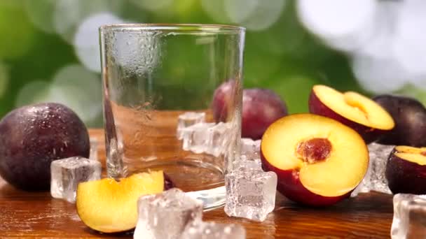 Pruimensap gegoten in glas met ijs en fruit op tafel — Stockvideo