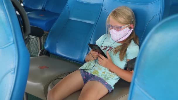 Child girl use smartphone on seat with red cross sign on ferry boat — Stock Video