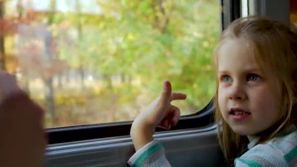 Child girl looks out window of train in carriage during journey — Stock Video