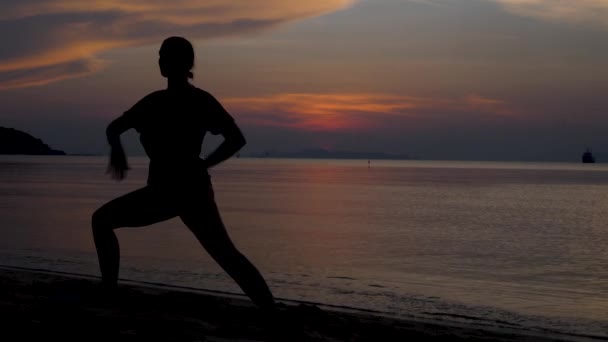 Mladé ženy silueta dělá jógu na pláži při západu slunce — Stock video