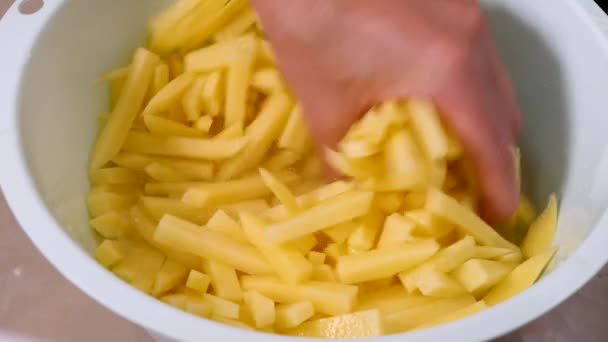 Chefs hands mix raw and sliced potatoes in white bowl — Stock Video