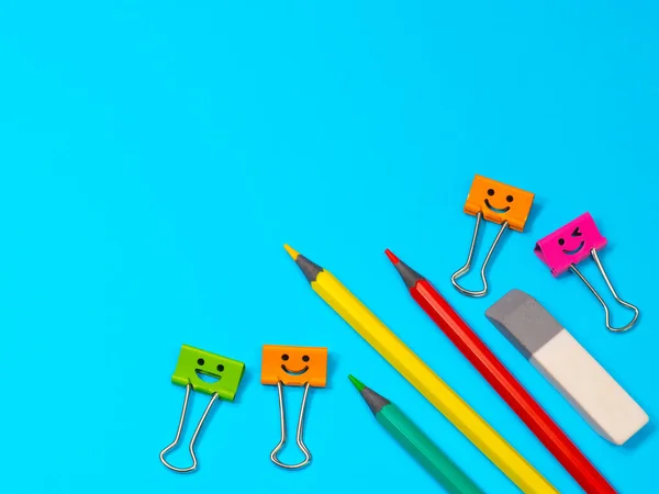 Smiles Binder Clips with Yellow, Green and Red Pencils on Blue Background Stock Image