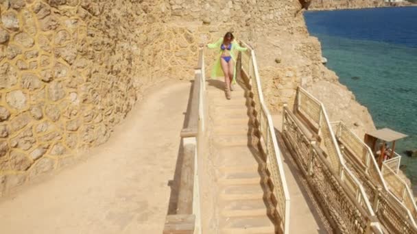 Vrouw in Licht Groene Pareo wandelt langs Observation Deck op Rock Near Sea — Stockvideo