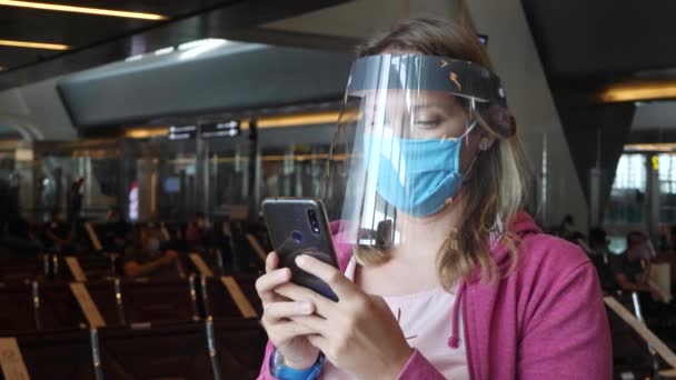 Γυναίκα με ιατρική μάσκα και ασπίδα προσώπου στο αεροδρόμιο — Αρχείο Βίντεο