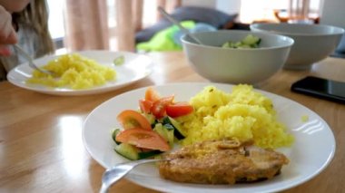 Salata dilimlenmiş domates ve salatalık dilimleri servis edilen zerdeçal pilavlı pirinç tabağı.