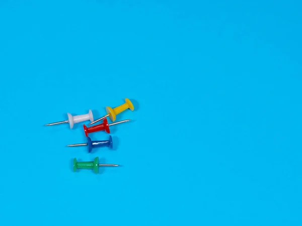 Color push pins on blue background for copyspace