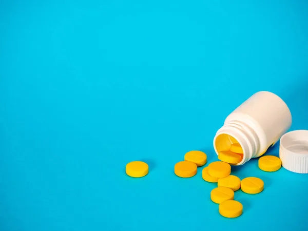 Sarı haplar ve plastik beyaz şişe.