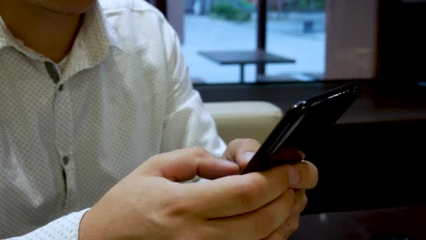 Mann im weißen Hemd plaudert auf schwarzem Handy — Stockvideo