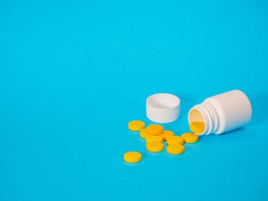 Sarı haplar ve plastik beyaz şişe.