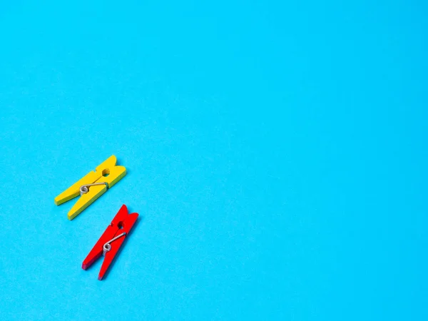 Pinzas de tela de madera amarilla y roja sobre fondo azul — Foto de Stock