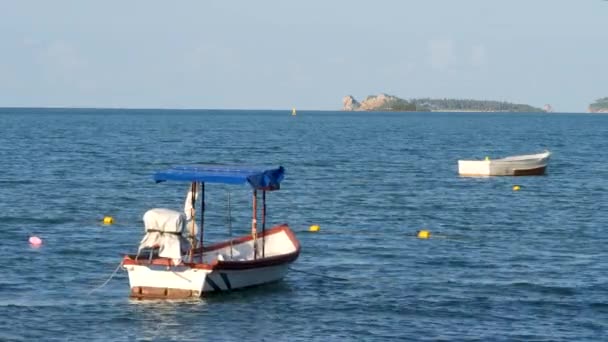 Small wooden fishing motorboat floating on blue sea water near coastline — Stock Video