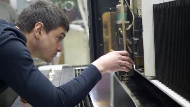 Ο αρσενικός χειριστής μηχανών εισάγει τα στοιχεία στο βιομηχανικό ψηφιακό CNC λέιζερ — Αρχείο Βίντεο