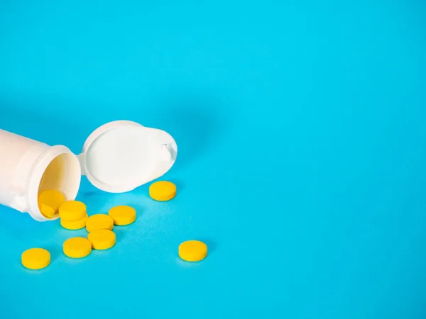 Sarı haplar ve plastik beyaz şişe.