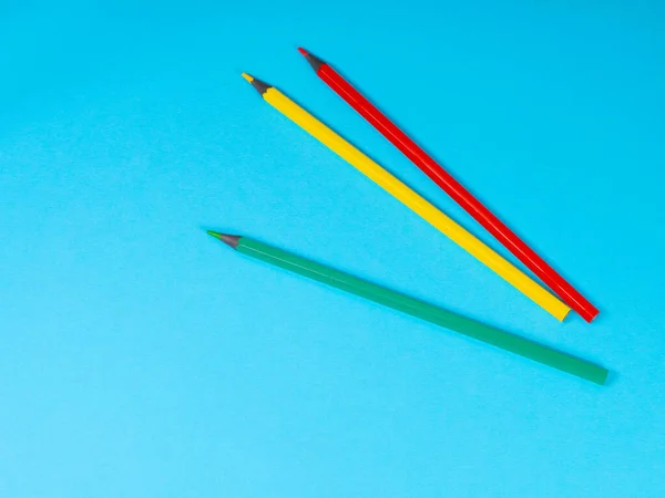 Красные, желтые и зеленые карандаши на синем фоне — стоковое фото