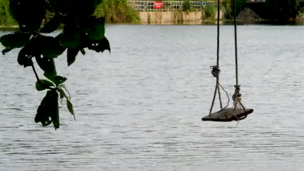 Одинокие качели на водном фоне — стоковое видео