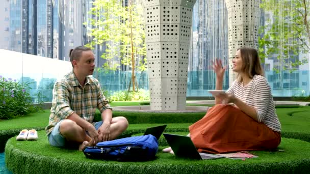 Colaborador adulto joven discute nueva idea se sienta en la hierba verde en la oficina del espacio de coworking — Vídeos de Stock