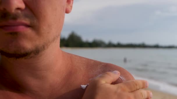 Onherkende man toe te passen sunblock lotion op lichaam op zee kust achtergrond — Stockvideo