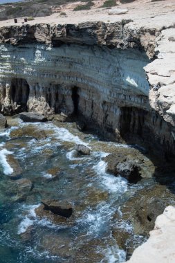 Ayia Napa Deniz Mağaraları ve Kıbrıs Rum Kesimi 'ndeki Manzaralı Akdeniz Kıyısı Kayalar, Resifler ve Açık Mavi Su ile Dikey Seyahat Fotoğrafları. Yüksek kalite fotoğraf