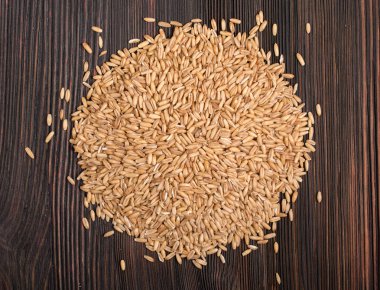 Yulaf bir eski koyu ahşap tahta üzerinde soyulmamış tohumları. Yakın çekim. Üstten görünüm.