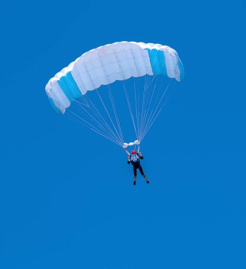 Mavi gökyüzü backgroun üzerinde beyaz ve mavi paraşüt ile Skydiver