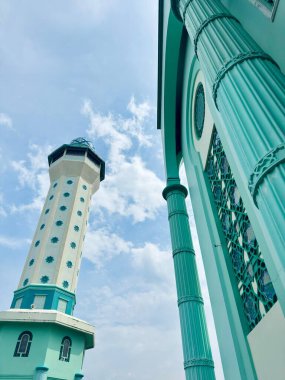 Stunning architecture of a vibrant turquoise mosque with a tall minaret against a beautiful blue sky, perfect for travel and cultural insights