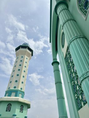 Majestic mosque minaret reaching for cloudy skies, inspiring faith and architectural wonder, perfect for travel blogs and cultural explorations