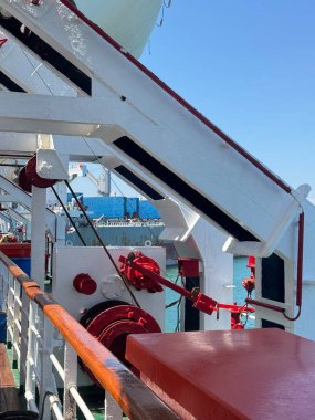 Modern ship deck equipment and safety systems detail with clear blue sky and ocean horizon, conveying marine engineering and maritime operations