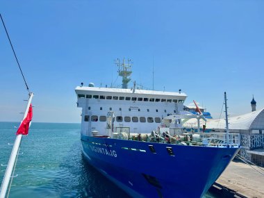 Majestic cargo ship docked at bustling port under clear blue sky, ready for global transport and commerce