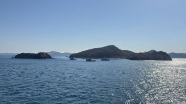 Serene ocean voyage passes lush tropical islands under a clear blue sky, offering peaceful escape and stunning natural beauty for your next project.