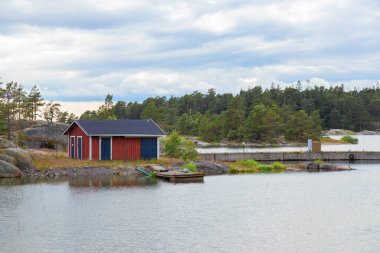 Beautiful view of wooden boat shed on the shore of the Baltic Sea in a cozy fishing Finnish village. Traditional Nordic architecture and peaceful coastal lifestyle