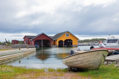 Finlandiya 'nın Baltık Denizi kıyısındaki bir balıkçı kasabasında geleneksel barakaların yanında küçük bir tekne. Huzurlu kıyı yaşamı, İskandinav mirası ve deniz kültürü